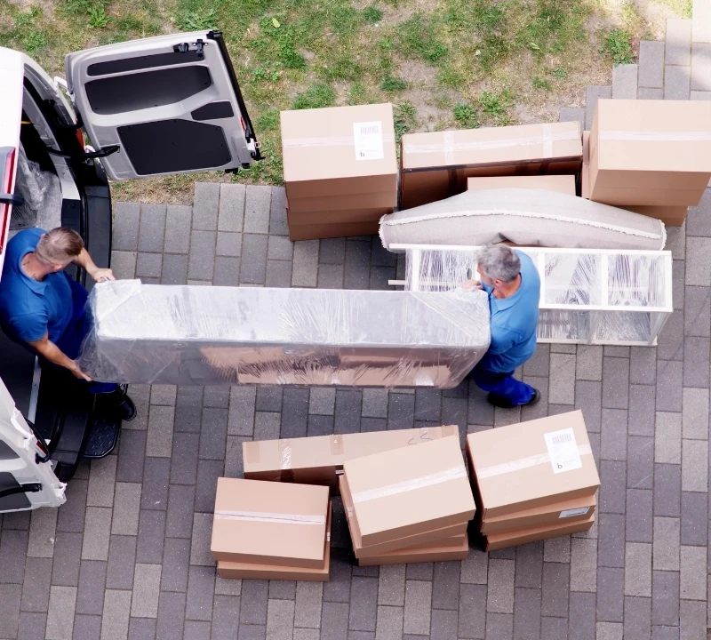 Umzugshelfer tragen verpacktes Möbelstück in Transporter – Umzugsunternehmen Detmold